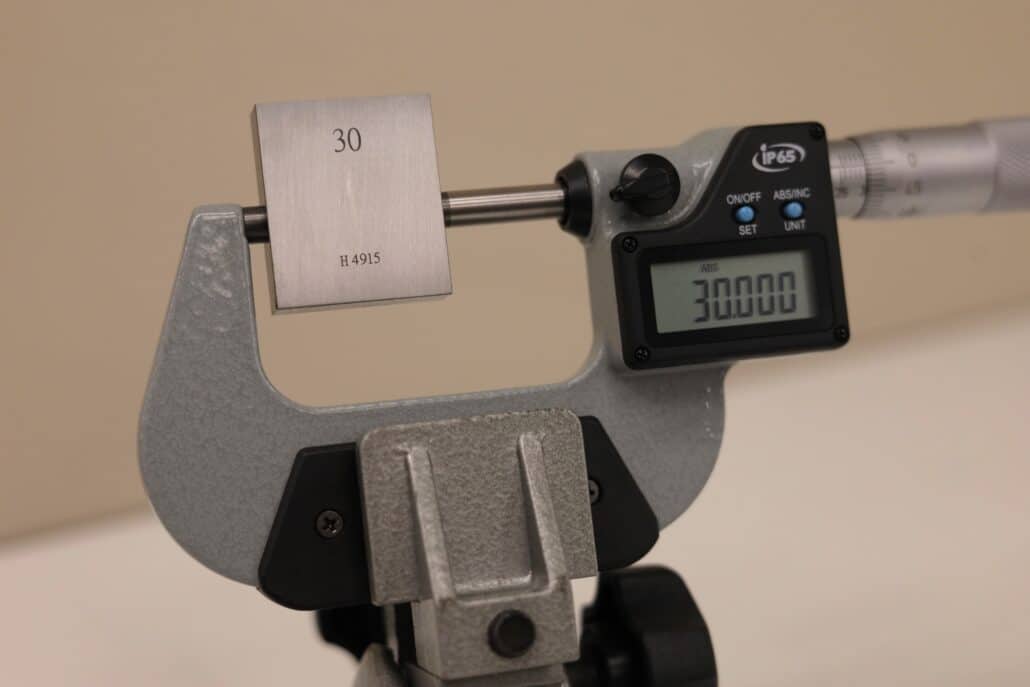 Measuring Instruments and Tolerances: Making the Right Choice 3 Micrometro digitale che misura un blocchetto campione da 30 mm, controllo dimensionale di alta precisione per tolleranze strette in laboratorio qualità.